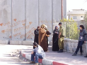 anziane palestinesi hanno appena scavalcato il muro, un soldato le ferma e controlla i loro documenti.